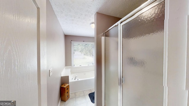 full bath featuring tile patterned floors, a stall shower, a garden tub, and a textured ceiling