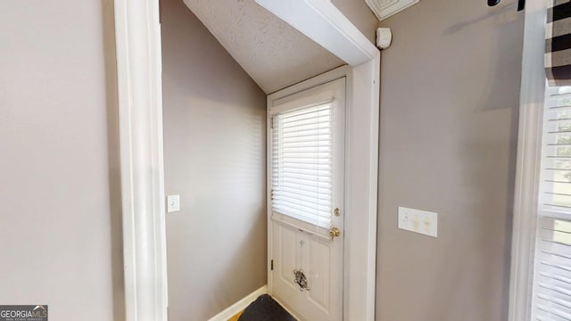 doorway featuring lofted ceiling and baseboards