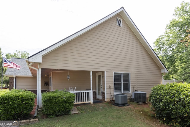 back of property featuring central AC unit and a yard