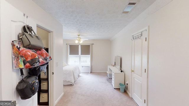 bedroom featuring a ceiling fan, visible vents, baseboards, a textured ceiling, and light colored carpet