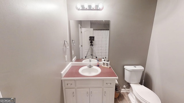 full bathroom featuring curtained shower, baseboards, toilet, wood finished floors, and vanity
