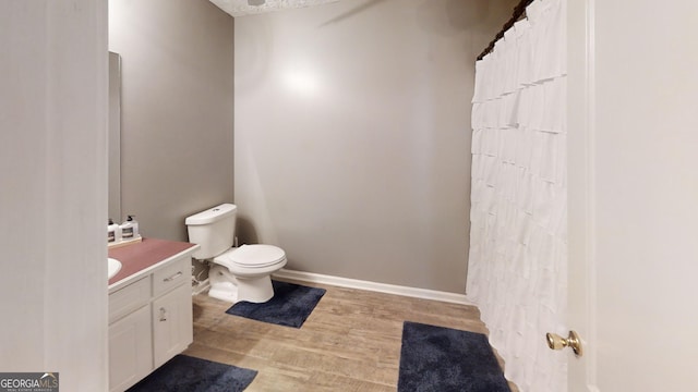 full bath featuring wood finished floors, toilet, vanity, and baseboards