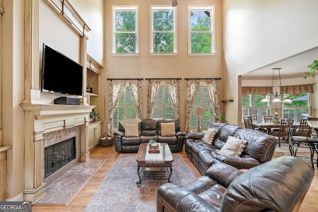 living area featuring a high end fireplace, a high ceiling, and light wood-type flooring