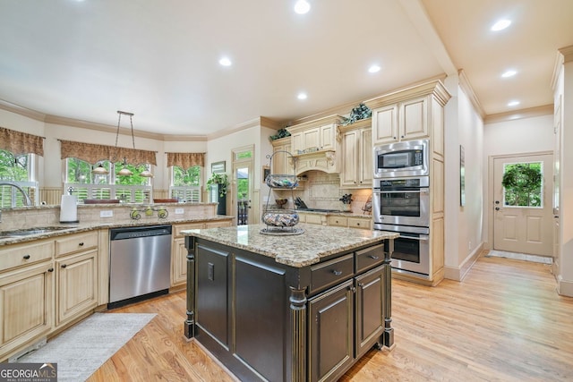 kitchen with a healthy amount of sunlight, decorative backsplash, appliances with stainless steel finishes, a sink, and cream cabinetry