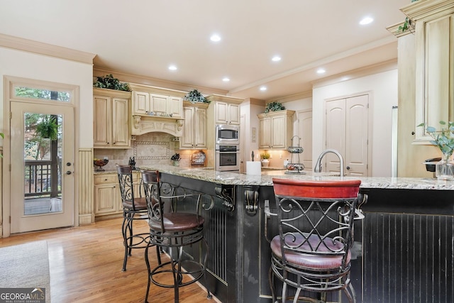 kitchen with cream cabinetry, appliances with stainless steel finishes, a breakfast bar area, and tasteful backsplash
