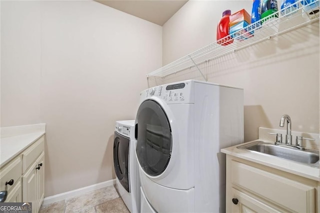 washroom with a sink, baseboards, and washer and dryer