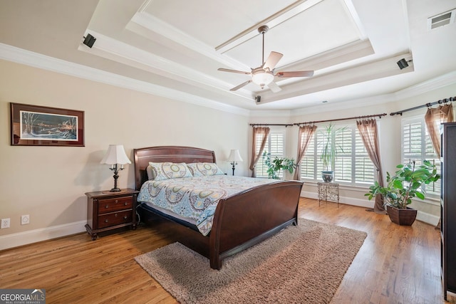 bedroom featuring visible vents, ornamental molding, wood finished floors, baseboards, and a raised ceiling