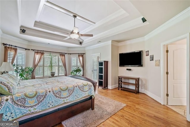 bedroom with crown molding, a tray ceiling, baseboards, and wood finished floors