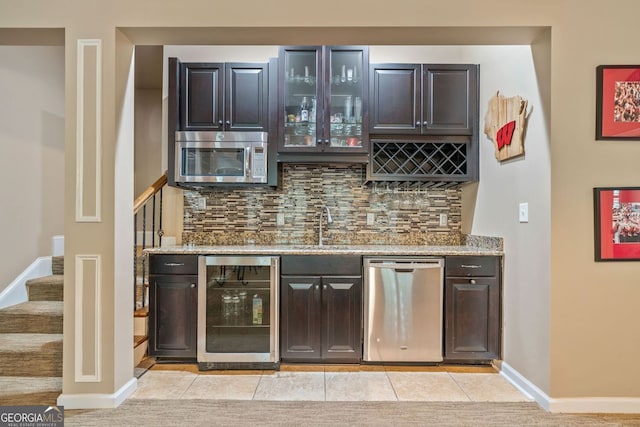 bar with wine cooler, indoor wet bar, stairway, a sink, and appliances with stainless steel finishes