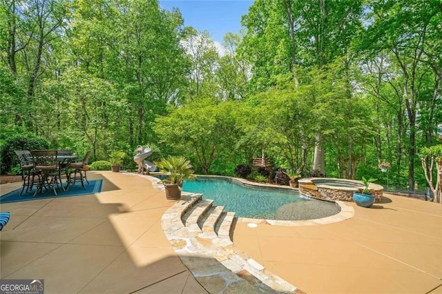 view of swimming pool with a patio, a pool with connected hot tub, and outdoor dining space