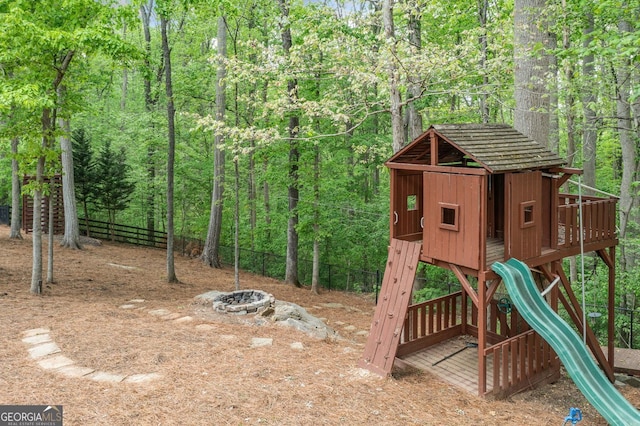 view of jungle gym with a view of trees and fence