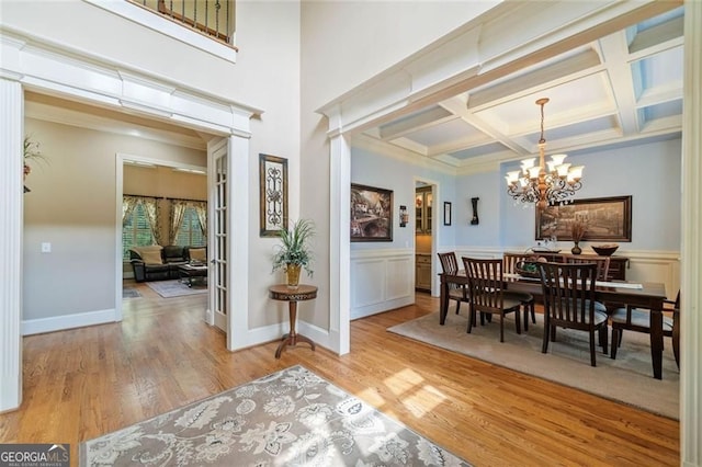 dining space featuring light wood-style floors, beamed ceiling, coffered ceiling, and a chandelier