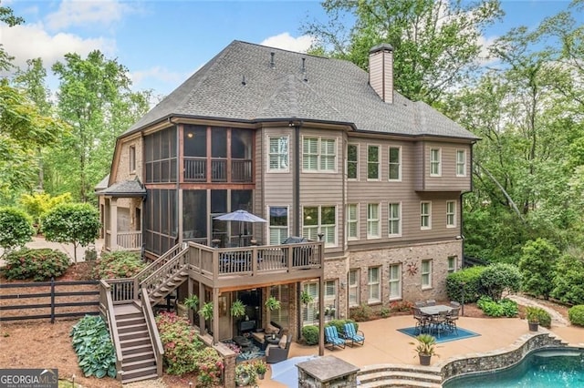rear view of property featuring a deck, stairway, an outdoor pool, a chimney, and a patio