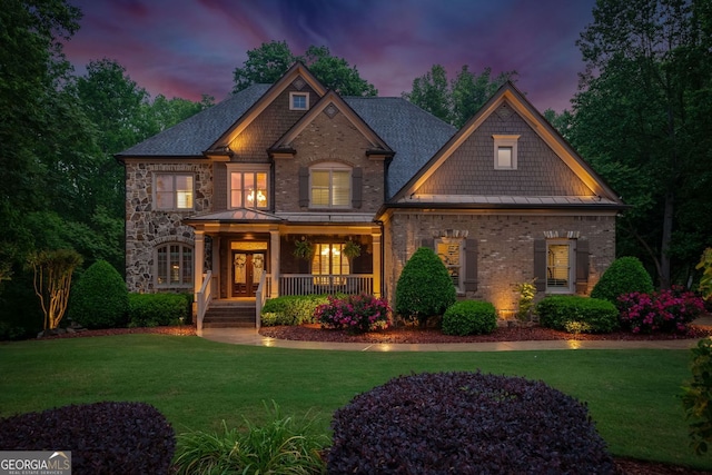 craftsman inspired home with a lawn, covered porch, and a shingled roof