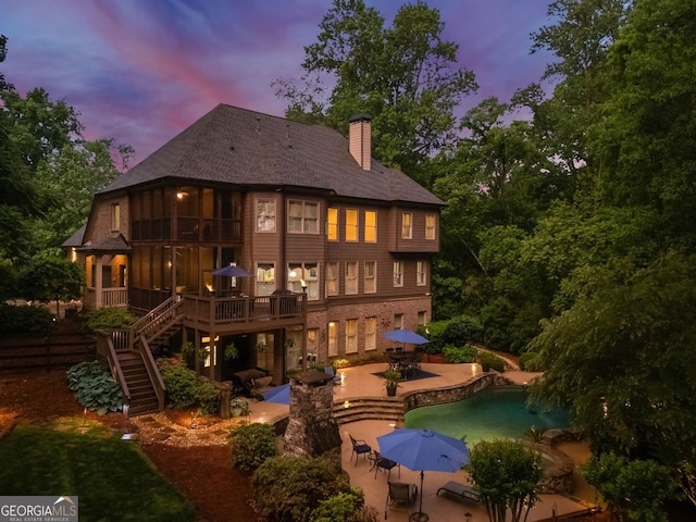 back of property featuring a chimney, a wooden deck, stairs, a patio area, and outdoor dining space