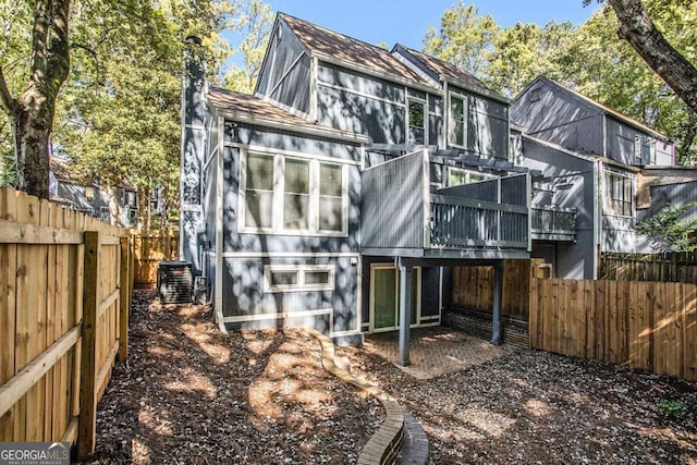 back of house with a deck, a fenced backyard, a shingled roof, and central AC