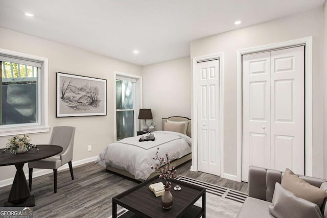 bedroom featuring wood finished floors, multiple closets, recessed lighting, and baseboards