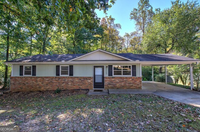 ranch-style house featuring brick siding, a carport, and driveway