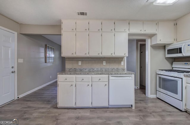 kitchen featuring white cabinetry, tasteful backsplash, visible vents, baseboards, and white appliances