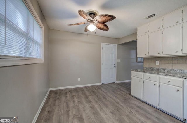kitchen with light countertops, ceiling fan, visible vents, baseboards, and white cabinets