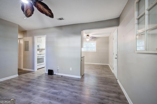 spare room with electric panel, baseboards, visible vents, a ceiling fan, and dark wood-type flooring