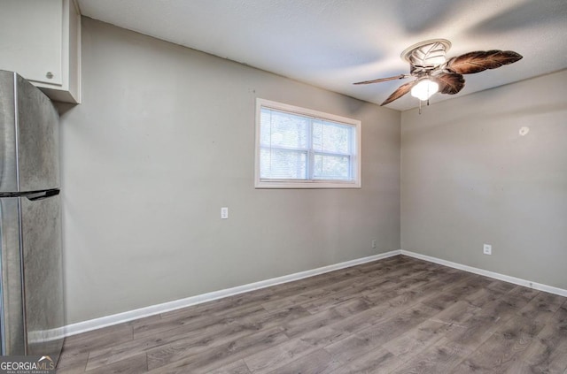 unfurnished room featuring wood finished floors, a ceiling fan, and baseboards