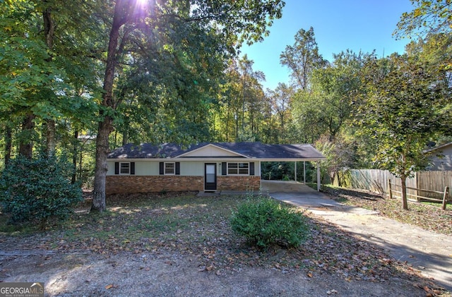 ranch-style house featuring brick siding, driveway, a carport, and fence