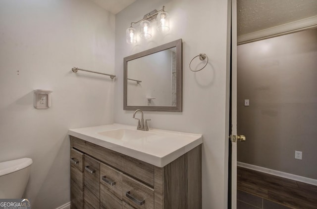 half bathroom featuring toilet, wood finished floors, vanity, and baseboards