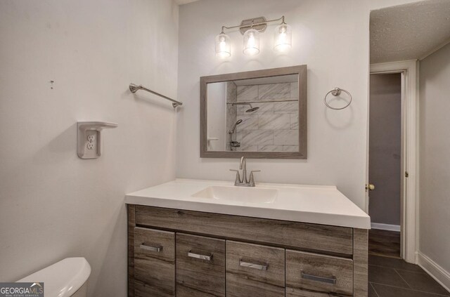 bathroom featuring tile patterned flooring, toilet, vanity, baseboards, and a shower