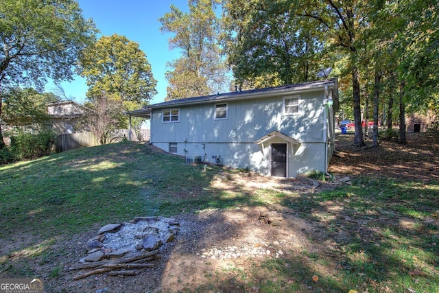 back of property featuring a lawn, central air condition unit, and fence