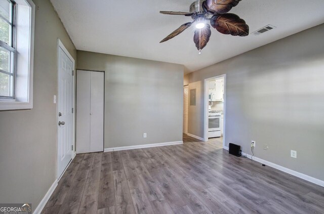 empty room with a ceiling fan, visible vents, wood finished floors, and baseboards