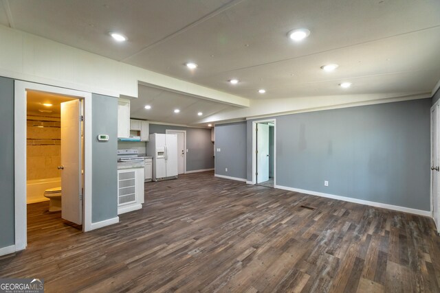 unfurnished living room featuring lofted ceiling with beams, dark wood-style floors, recessed lighting, and baseboards