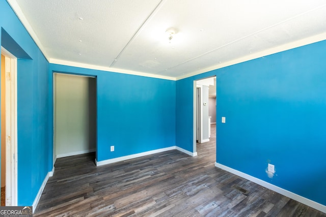 spare room with baseboards and dark wood-type flooring
