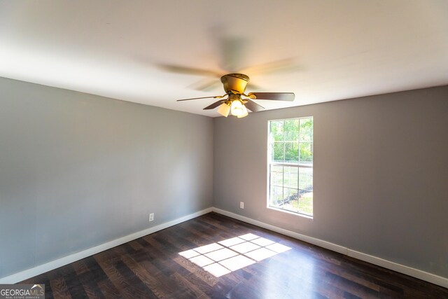 empty room featuring dark wood finished floors, a ceiling fan, and baseboards
