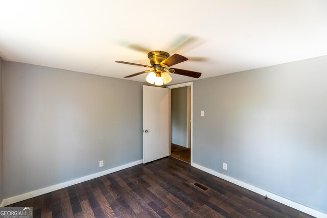 spare room featuring a ceiling fan, visible vents, dark wood-style flooring, and baseboards