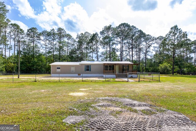 rear view of property featuring metal roof, a yard, and fence private yard