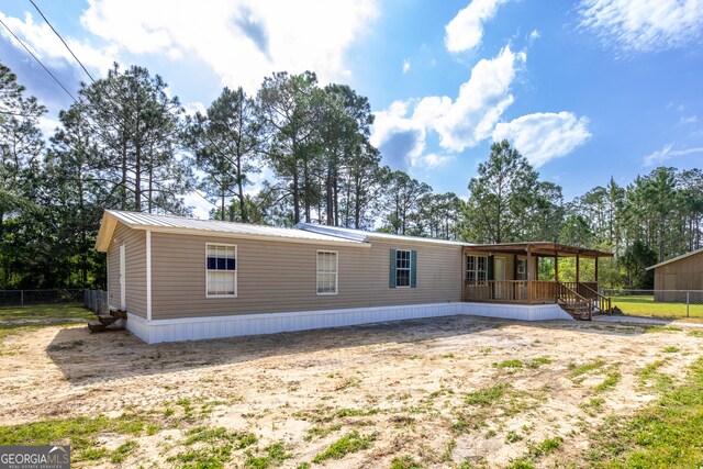 rear view of property with fence, covered porch, and metal roof