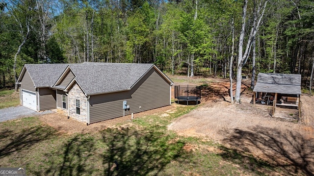 241 Simmons Dr Unit 6B, Ellijay, GA 30536 - view of home's exterior featuring a wooded view, stone siding, an outbuilding, roof with shingles, and a garage