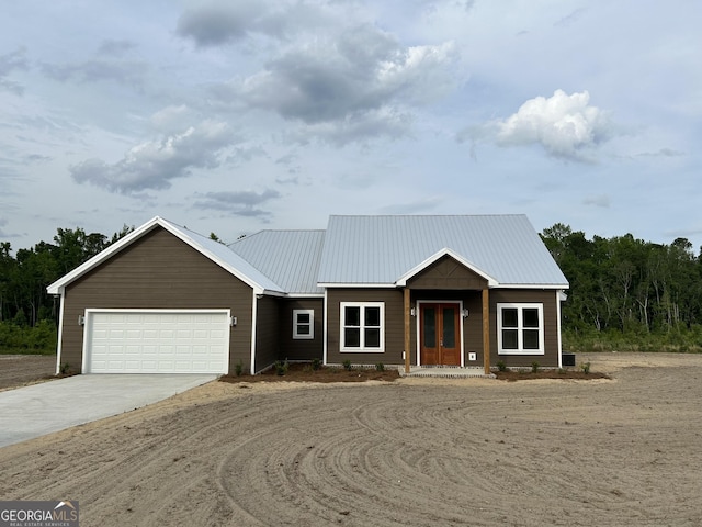 1159 Paris Ave, Swainsboro, GA 30401 - view of front of house with driveway, a garage, metal roof, and french doors