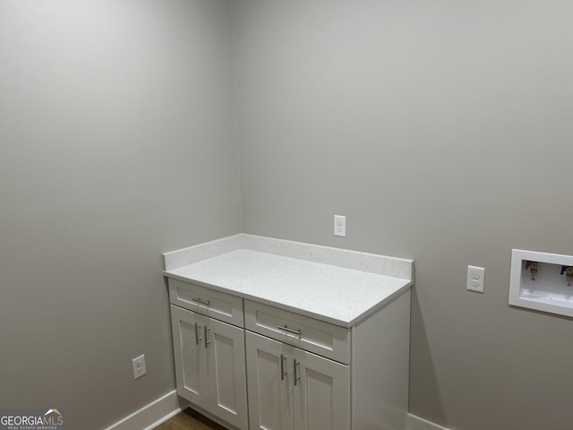 laundry area featuring baseboards, cabinet space, and washer hookup