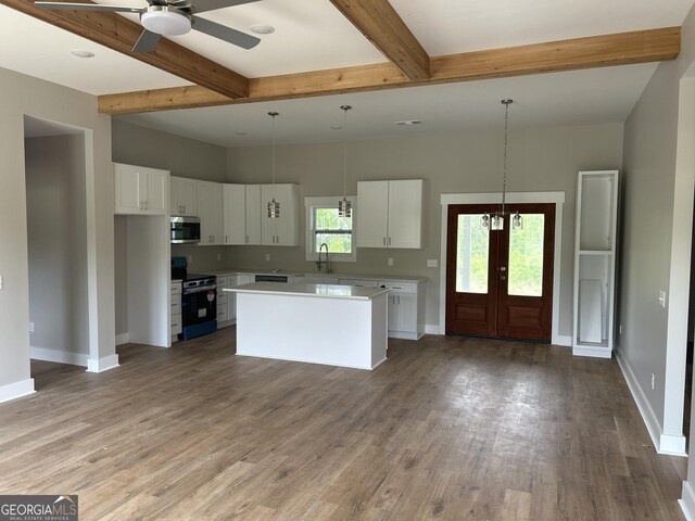 kitchen with white cabinets, a sink, appliances with stainless steel finishes, light countertops, and baseboards