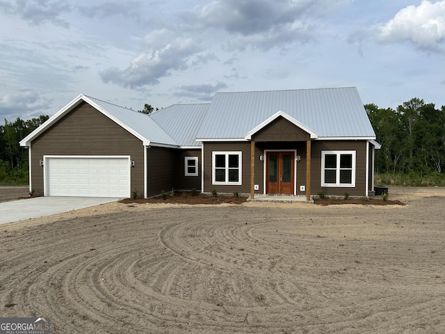 1159 Paris Ave, Swainsboro, GA 30401 - view of front of house with concrete driveway, an attached garage, french doors, and metal roof