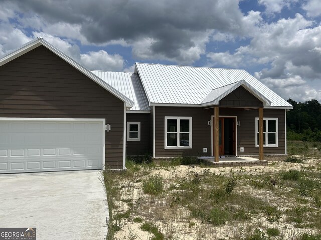 view of front of home with metal roof, driveway, a garage, and covered porch