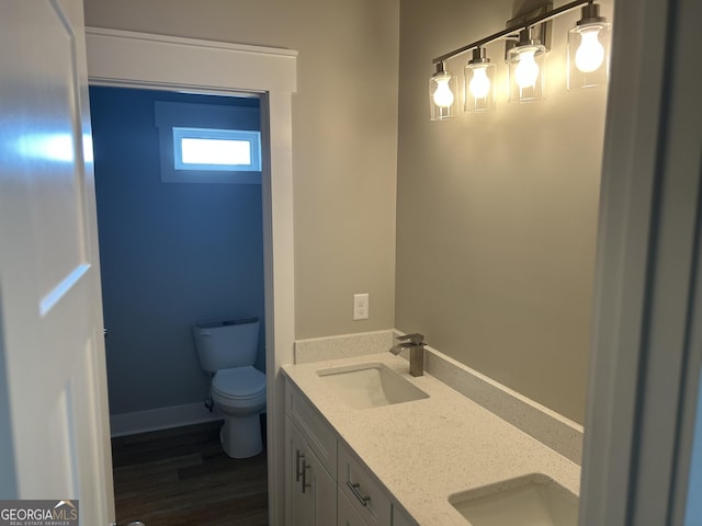 bathroom with toilet, double vanity, a sink, and wood finished floors