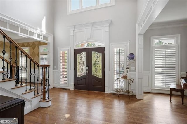 foyer with french doors, wood finished floors, a healthy amount of sunlight, and stairway
