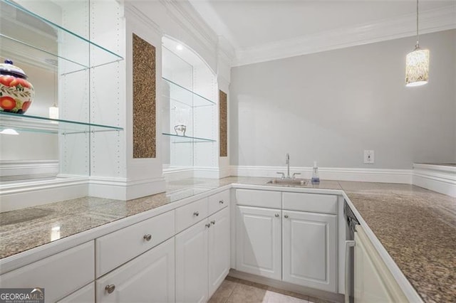 kitchen featuring ornamental molding, a sink, white cabinets, and decorative light fixtures