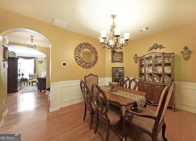 718 Province Pl SE, Atlanta, GA 30312 - dining area featuring a chandelier, arched walkways, light wood-style floors, a wainscoted wall, and a decorative wall