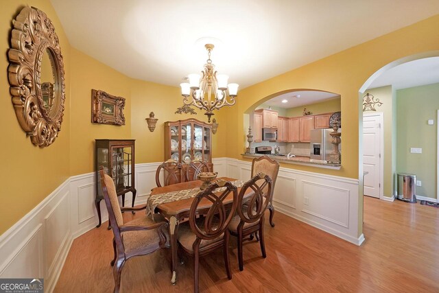 718 Province Pl SE, Atlanta, GA 30312 - dining room with a decorative wall, a chandelier, light wood-type flooring, arched walkways, and a wainscoted wall