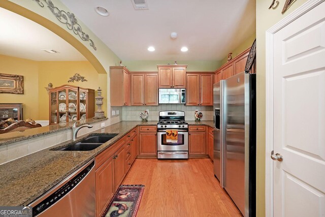 718 Province Pl SE, Atlanta, GA 30312 - kitchen with appliances with stainless steel finishes, arched walkways, a sink, dark stone countertops, and light wood finished floors