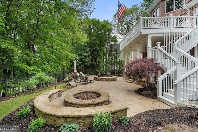 view of patio with an outdoor fire pit, stairway, and fence